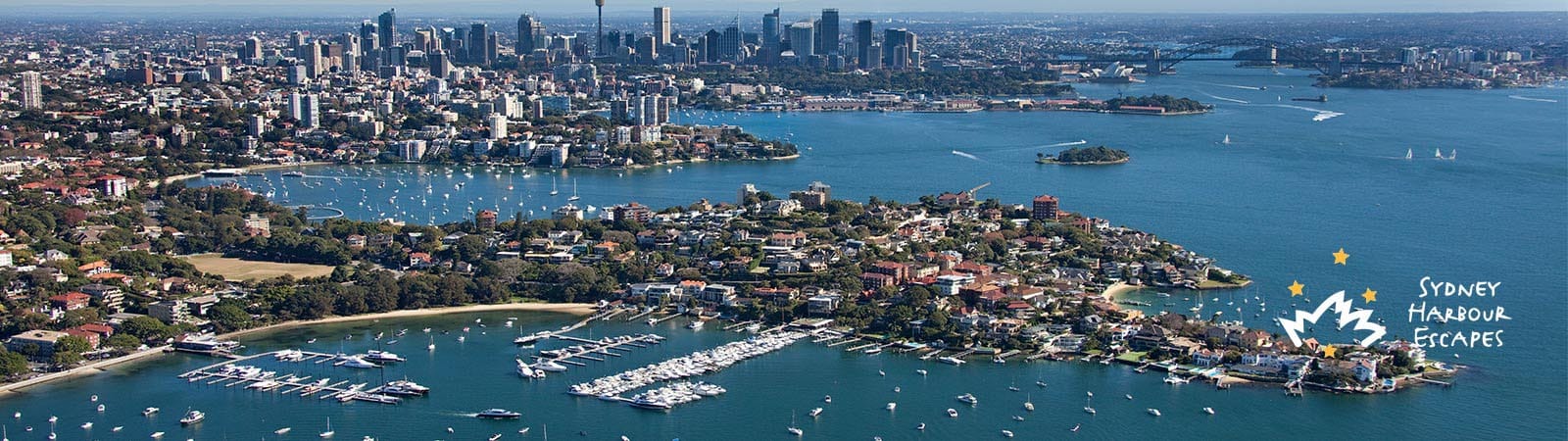 Sydney Harbour Escapes banner photo showing boat on water in front of harbour bridge and opera house